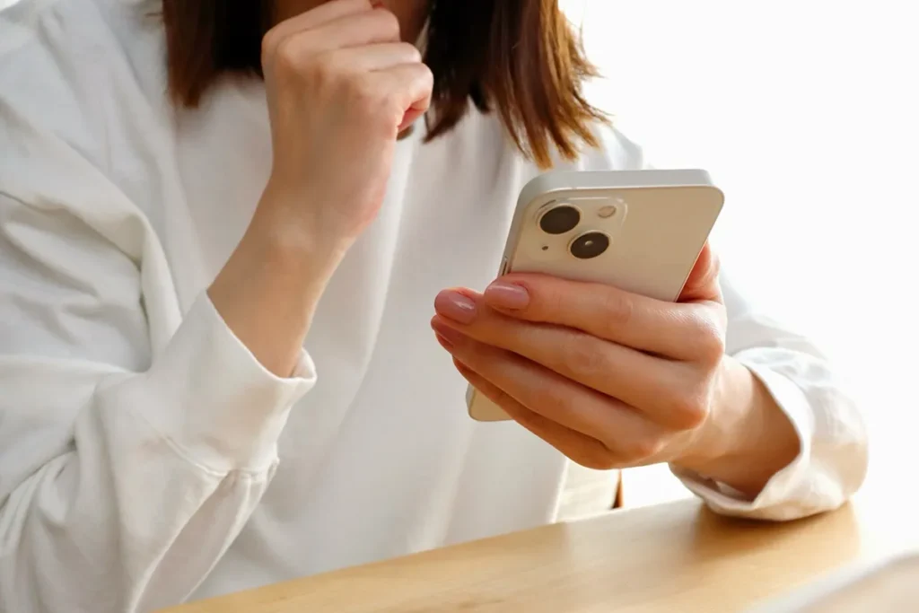 スマホを見ながら拳を握る女性